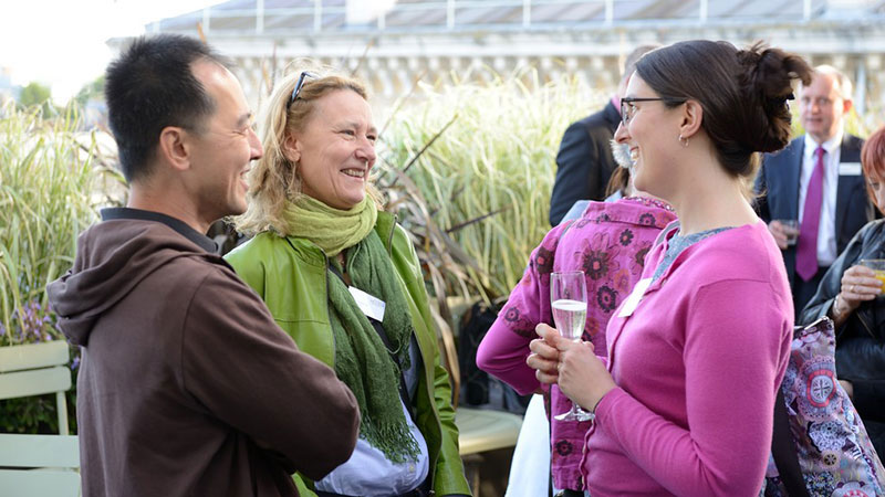 A man and two women talking and smiling at an event